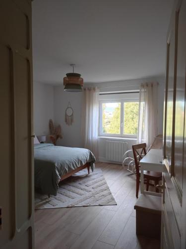a bedroom with a bed and a window and a desk at Logement cosy proche Cluny in Buffières