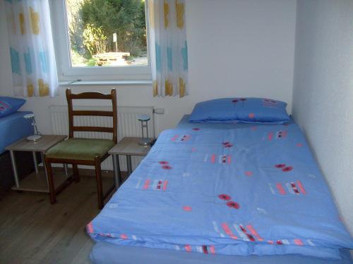 ein Schlafzimmer mit einem Bett, einem Stuhl und einem Fenster in der Unterkunft Ferienhaus Am Barenberg in Thülsfeld