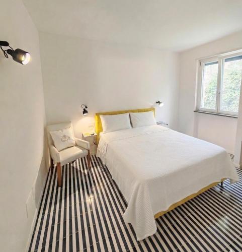 a white bedroom with a large bed and a chair at Minnelea Blue Retreat in Acciaroli