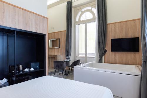 a bedroom with a bed and a tub and a tv at Kore Luxury Suite e Spa in Naples