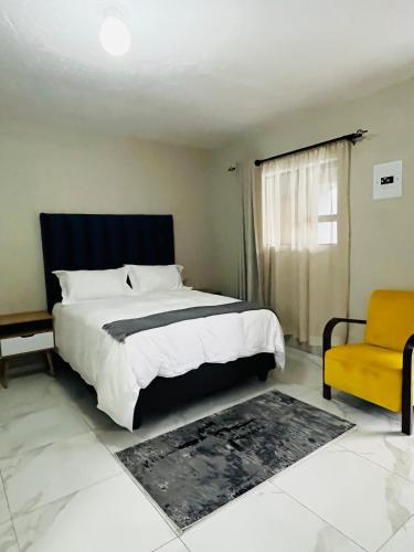 a bedroom with a large bed and a yellow chair at Rest Easy Guest House Pty Ltd Unit 5 in Boksburg