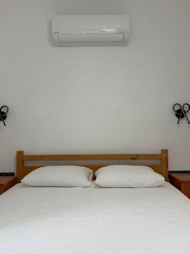a bed with two pillows and a air conditioner on the wall at Armeda Restoran ve Pansiyon in Datca