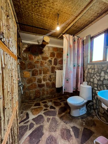 a stone bathroom with a toilet and a sink at Akagera Transit Lodge in Akagera