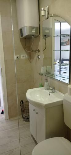 a bathroom with a sink and a toilet and a mirror at Apartman Vida in Zaton