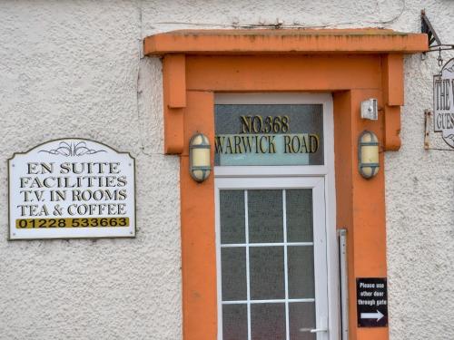 an orange door with a sign on a building at The Warren Guest House in Carlisle