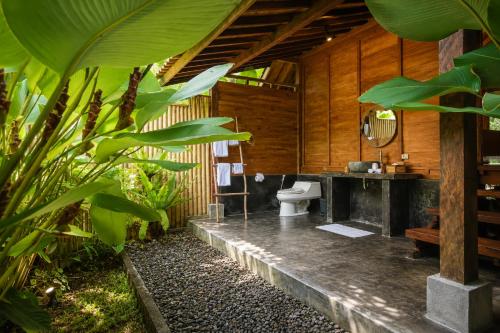 a bathroom with a toilet in a wooden building at The Payung House - Romantic Riverside Villa in Bebandem