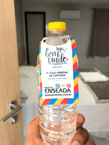 a person holding a bottle of water in their hand at Hotel Enseada Aeroporto in Recife