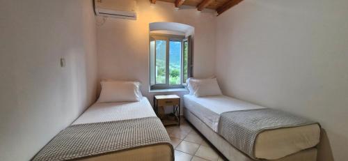 two beds in a room with a window at Vrisi House in Kiparission