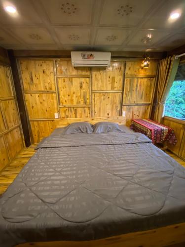 a large bed in a room with wooden walls at Corn family homestay in Làng Me