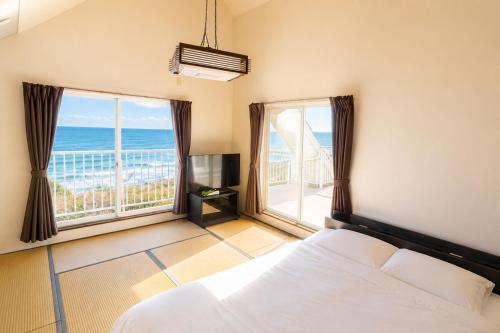 a bedroom with a bed and a view of the ocean at SORA Blue House, 海辺の隠れ家, ペットBBQ可, 全3寝室&リビングオーシャンビュー,一棟貸切 in Hokota
