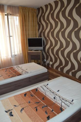 two beds in a room with a computer on a wall at Eos Hotel in Vidin