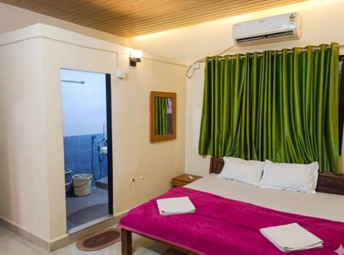 a bedroom with a bed and a green curtain at Caffe Bombay in Nagaon