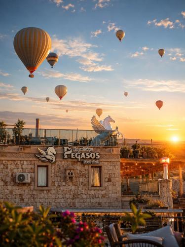 a group of hot air balloons flying over a building at Cappadocia Pegasos Cave Suite Hotel in Uçhisar