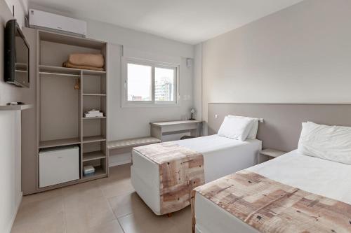 a small bedroom with two beds and a window at Tri Hotel Smart Santa Maria in Santa Maria