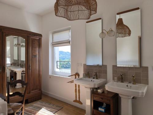 a bathroom with two sinks and two mirrors at Le Tilleul d'Hortense in Ussac