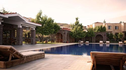 a swimming pool with two chairs next to a building at Cinarli Kasri in Gokceada Town