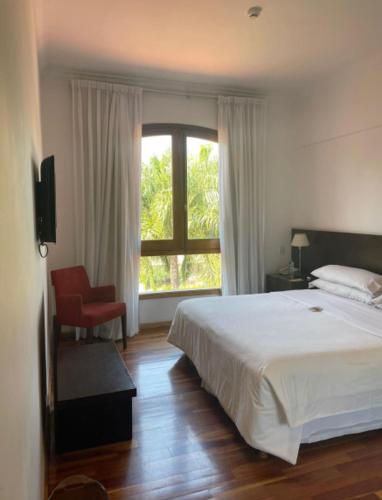 a bedroom with a bed and a window and a chair at Hotel Casino Catamarca in San Fernando del Valle de Catamarca