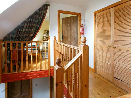 a wooden staircase in a house with a wooden door at The Smiddy - S4278 in Lochearnhead