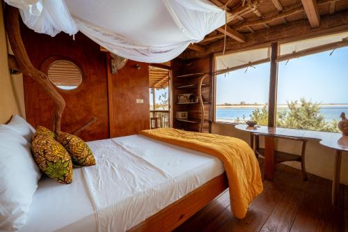 a bedroom with a canopy bed in a boat at Les Collines De Niassam in Palmarin