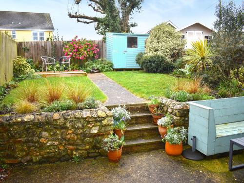 a garden with a stone wall and some potted plants at Little Hog Cottage in Seaton