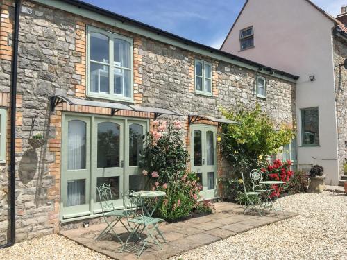 a stone house with tables and chairs in front of it at Meadow View-Uk34416 in Cheddar