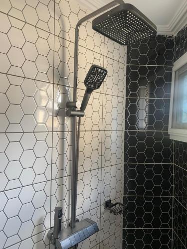 a shower in a bathroom with black and white tiles at Modern 1bedroom apartment in Douala