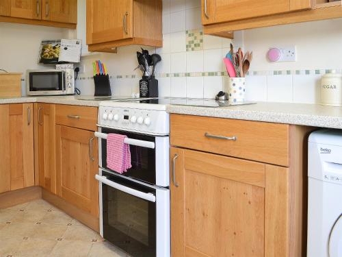 a kitchen with wooden cabinets and a white stove top oven at Poplar Bungalow in Lyng