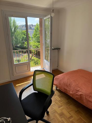 a room with a chair and a bed and a window at Grand appartement dans une résidence à caen in Caen