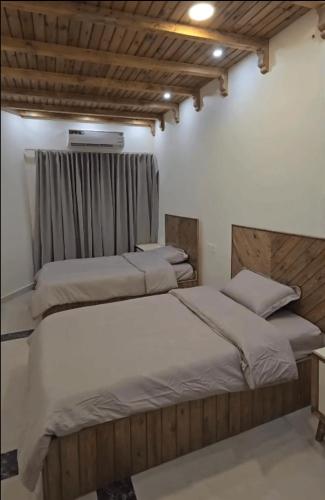a bedroom with two beds and a window at Ezdan Residence إزدان رزيدينس in Unayzah