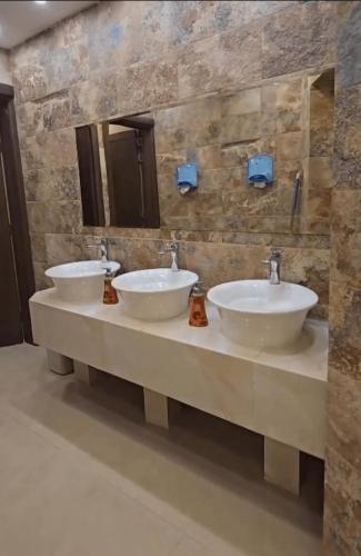 a bathroom with three sinks and a mirror at Ezdan Residence إزدان رزيدينس in Unayzah