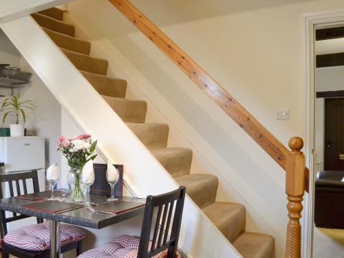a dining room with a table with a vase of flowers at Park View Cottage in Old Glossop