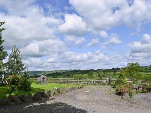 a field with a fence and a barn in the distance at Y Dderwen At Brynglas Farm in Llanfair Caereinion