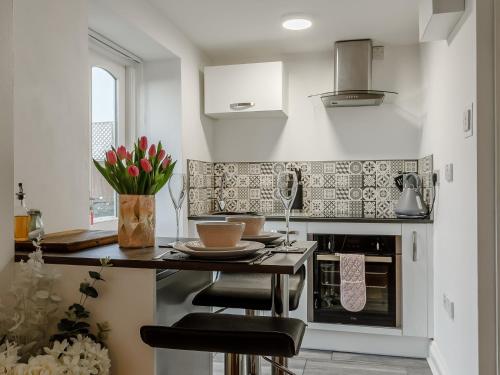 a kitchen with a counter with stools in it at Orchard View-Uk34417 in Cheddar