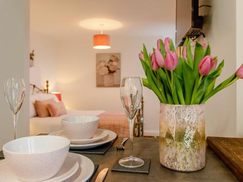 a table with a vase of pink tulips on it at Orchard View-Uk34417 in Cheddar