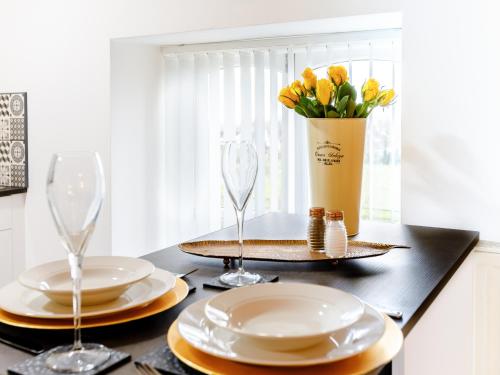 a table with plates and glasses and a vase of flowers at Tor View-Uk34415 in Cheddar