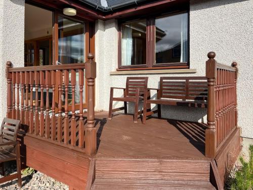 a wooden deck with two chairs and a bench at Nether Carness in North Ballachulish