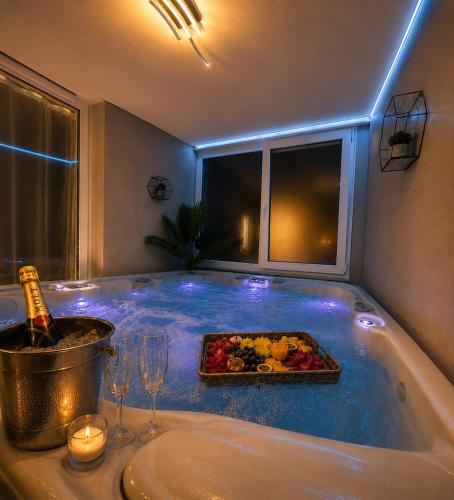 a bath tub with a tray of food and a bottle of wine at Luxor - Private Jacuzzi Boulevard Suites in Sibiu