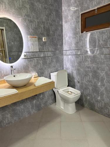 a bathroom with a toilet and a sink and a mirror at Residencial Convênios- Hotelaria e Turismo LDA in Luanda