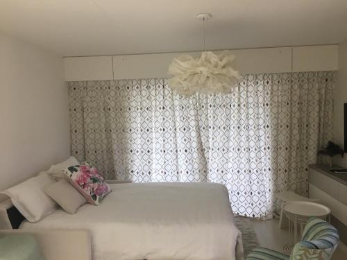 1 dormitorio con cama blanca y lámpara de araña en Studio Ile Cannes Marina, en Mandelieu-la-Napoule