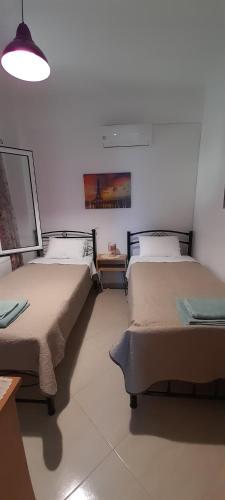 a room with two beds and a table and a lamp at Kate House in Agioi Apostoli