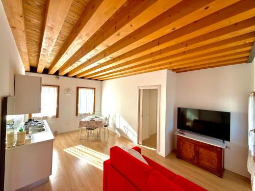 a living room with a red couch and a flat screen tv at Ca' Luciana Valdobbiadene in Valdobbiadene