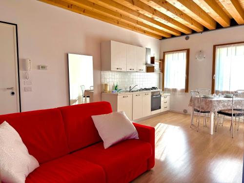 a living room with a red couch and a kitchen at Ca' Luciana Valdobbiadene in Valdobbiadene