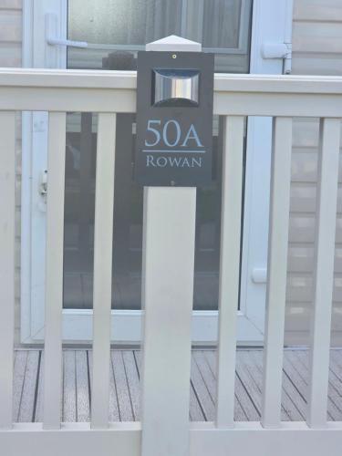 a sign on a white fence in front of a house at 50A ALDERLEY at Hoburne bashley in New Milton