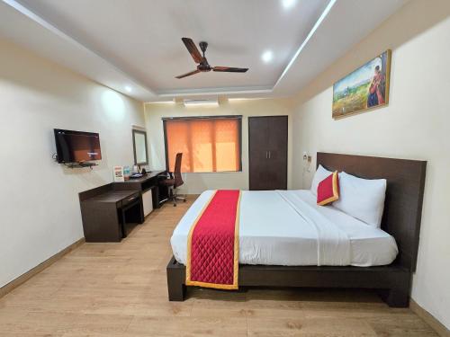 a hotel room with a bed and a desk and a television at Hotel Ashok Residency, Porur in Chennai