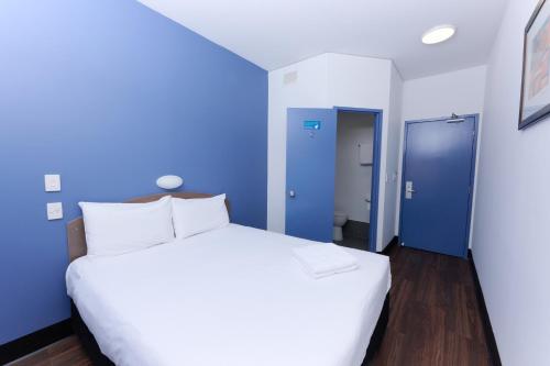 a large white bed in a room with blue walls at ibis Budget Perth Airport in Perth