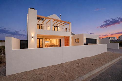 a large white house with a sunset in the background at Yzer4You in Yzerfontein