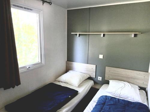 two beds in a small room with a window at Camping de Bourges in Bourges