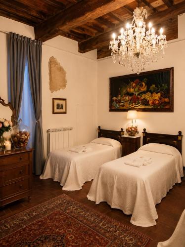 a room with two beds and a chandelier at Le Dimore della Seta - Palazzo Busdraghi in Lucca