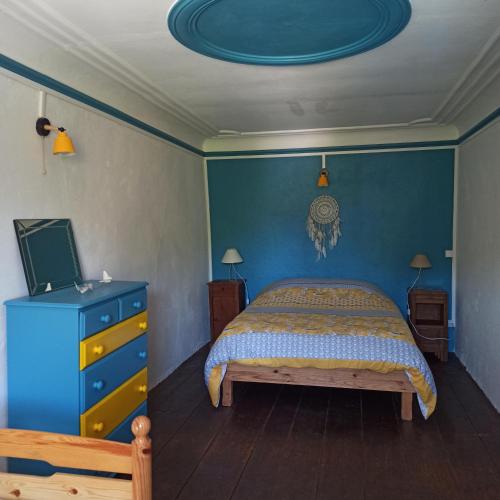 a bedroom with a bed and a blue wall at La Maison des 2L in Saint-Médard