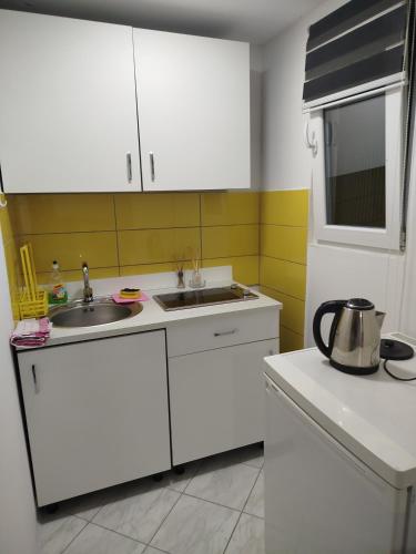 a kitchen with white cabinets and a sink at Apartman Deni in Tuzla